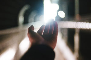 hand being outstretched towards the end of a lighted tunnel